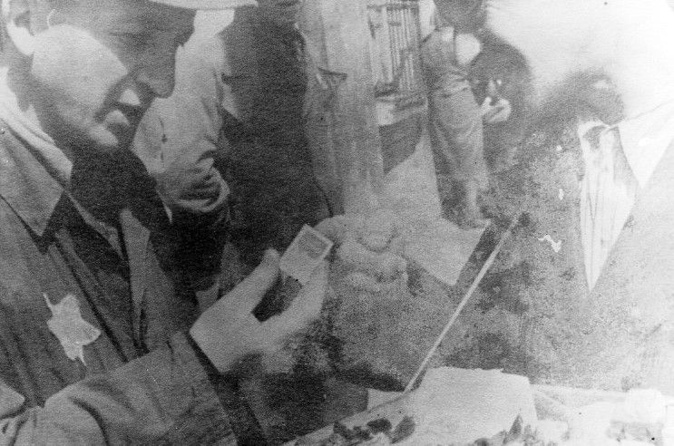 The photographer Mendel Grosman buying a package of saccharin from a street vendor in the Lodz ghetto.